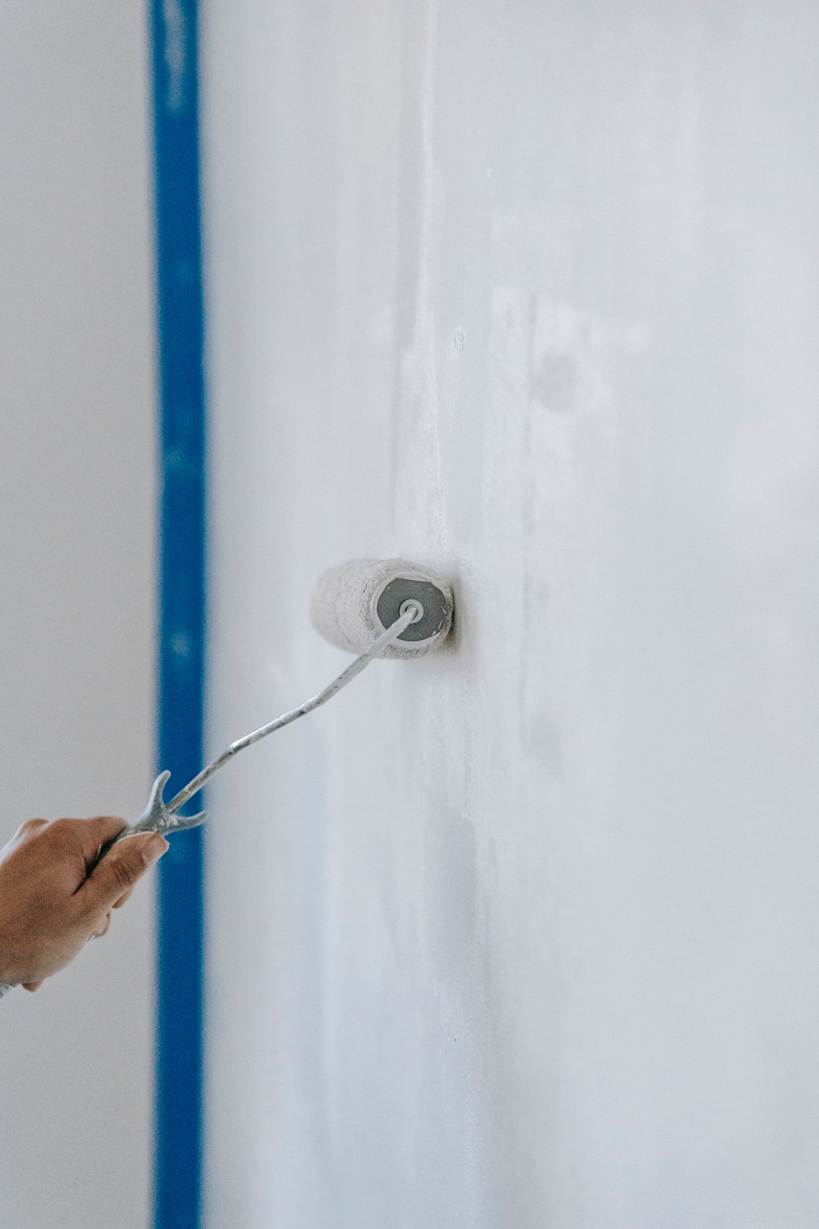 Rodillo aplicando pintura blanca sobre una pared texturizada